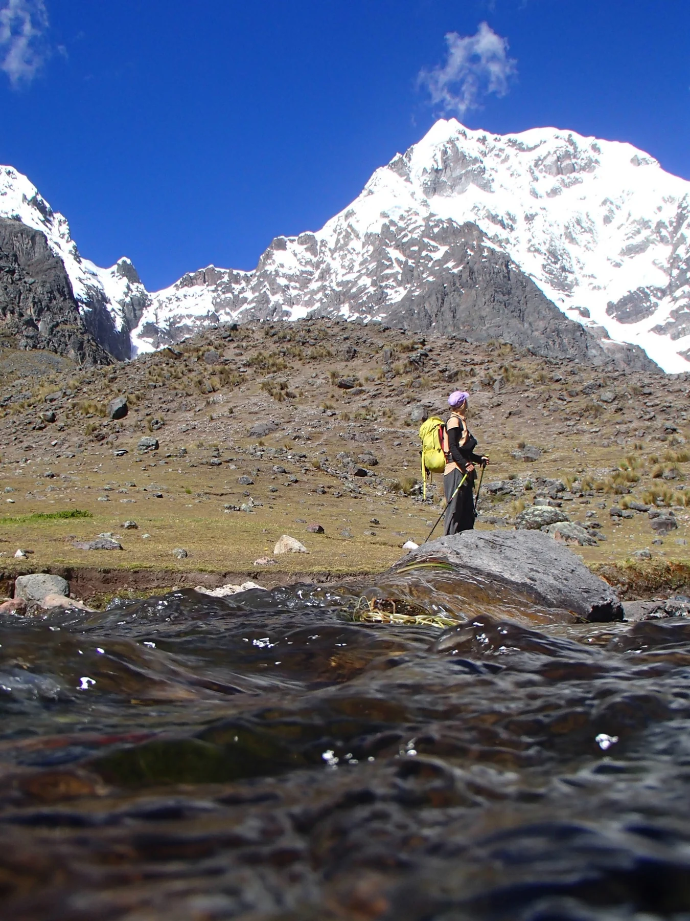 Caminante junto a un arroyo con el Ausangate al fondo
