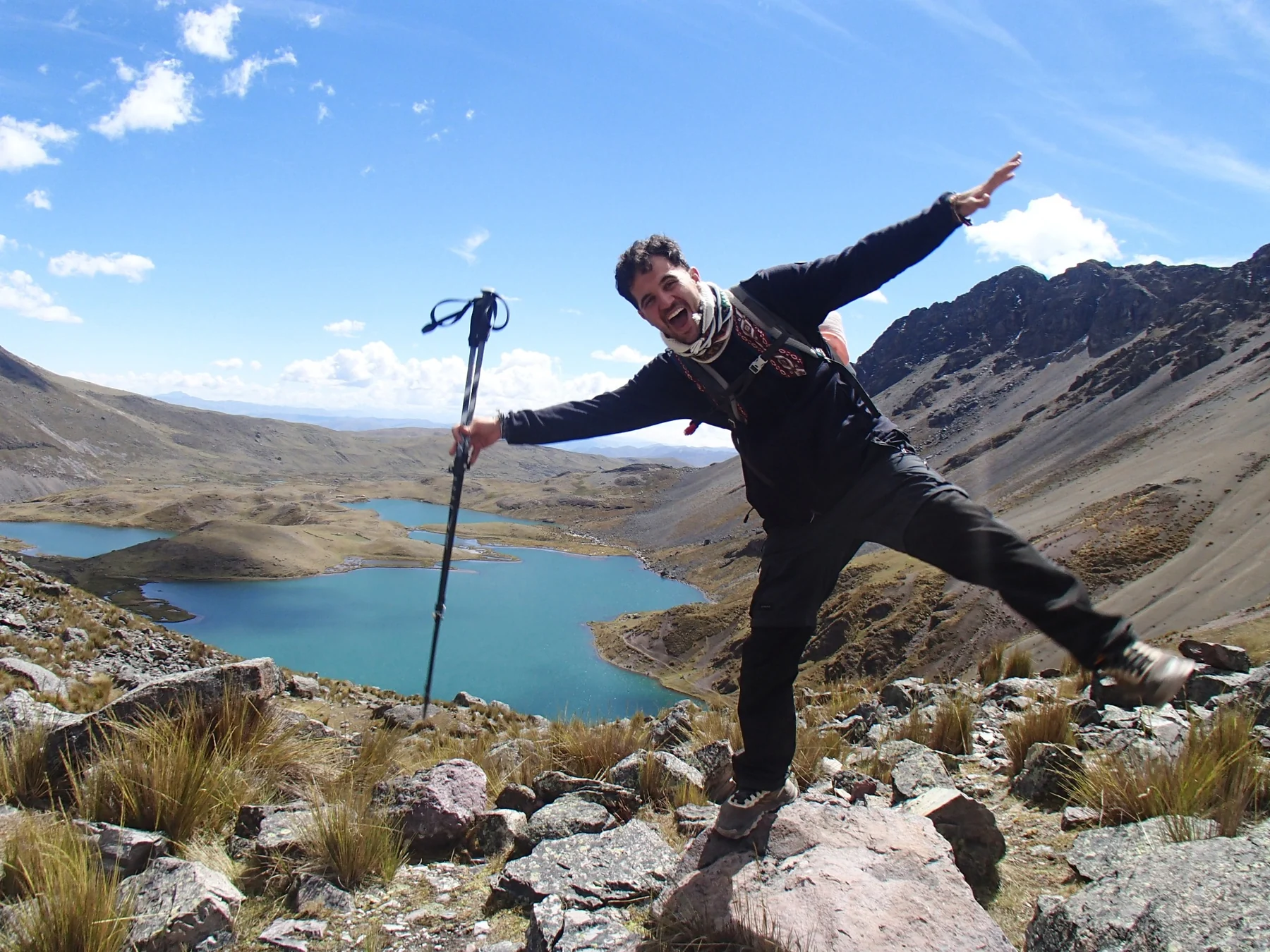 Viajero celebrando con lagunas de altura al fondo